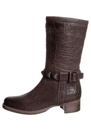 Bottine en cuir marron foncé avec une texture froissée, détail de boucle sur le côté et clous en pyramide. Talon carré pour plus de hauteur.