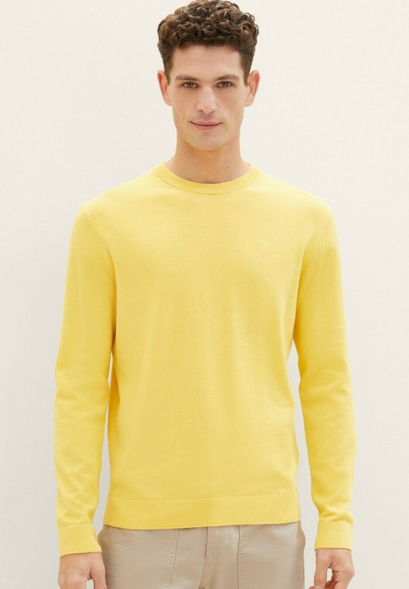 Geel gebreid sweater met een ronde halslijn, lange mouwen en geribbelde manchetten. De stof lijkt glad met een subtiele textuur.