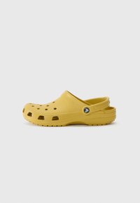 Yellow clogs made of lightweight material, featuring ventilation holes, curved back, and a round logo accent on the side. Smooth texture.