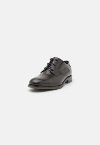 Zapato de vestir de cuero marrón con un acabado suave, punta redonda y diseño de cordones, que presenta un logotipo sutil y un panel lateral texturizado.