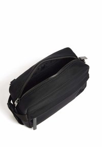 Borsa a tracolla in nylon nero con doppia cerniera, forma rettangolare, superficie tessurizzata e un motivo interno sottile. Dotata di tracolla regolabile.