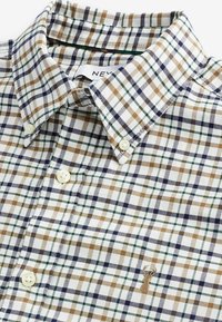 Geruite shirt in witte, groene, marineblauwe en bruine tinten; met een button-down kraag en crèmekleurige knopen; bevat een klein geborduurd logo.