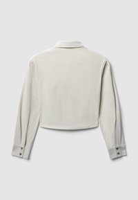 Camicia corta di colore crema con maniche lunghe, texture a costine e polsini abbottonati. Presenta un colletto classico e un design minimalista.