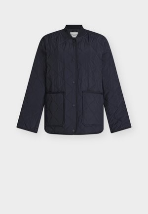 Tumesinine tikandiga jakk, millel on rombikujuline muster, soonikkoeline krae, trukk-nööbid ja kaks esist taskut. Kerge kangas, sileda tekstuuriga.