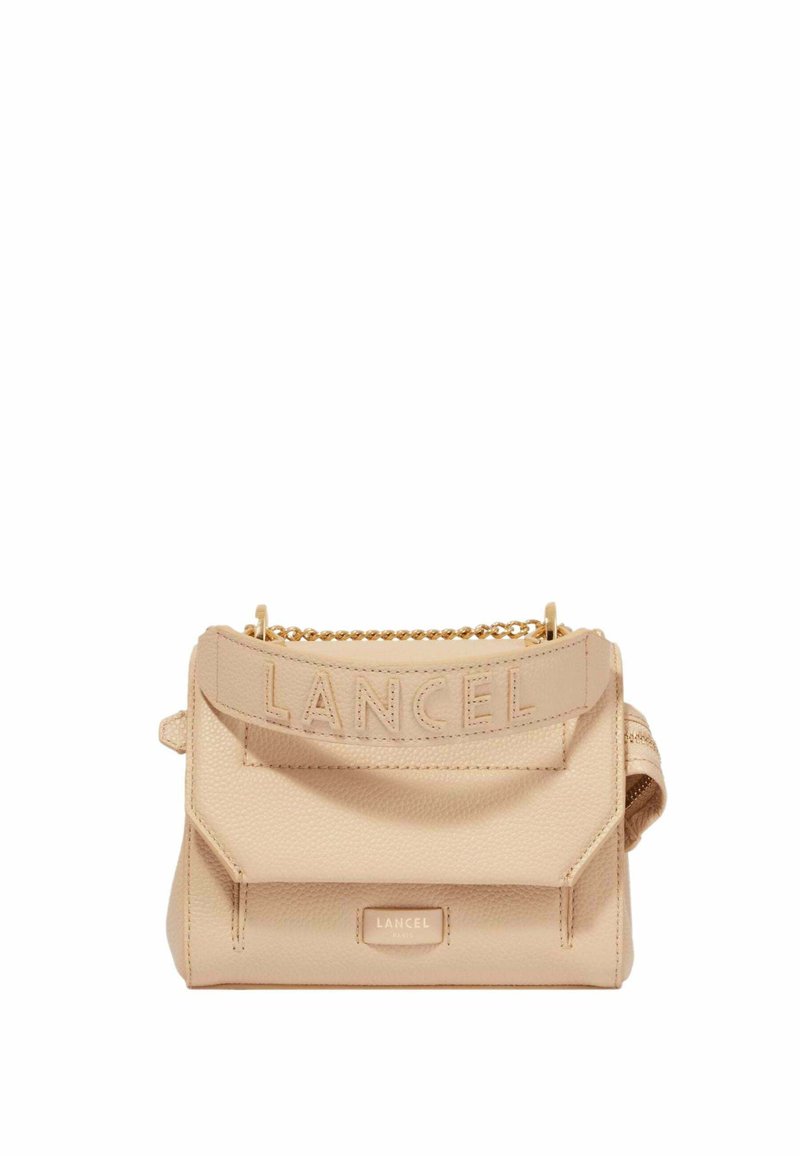 Sac à main en cuir beige avec une surface texturée, logo en relief sur la sangle et une bandoulière en chaîne dorée. Forme rectangulaire compacte.