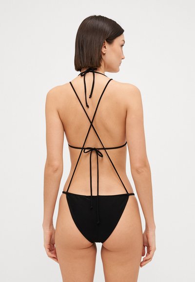 Bikini negro con finas tiras de sujeción, que presenta un diseño de espalda descubierta y una parte inferior de cobertura mínima. Textura suave y silueta clásica.