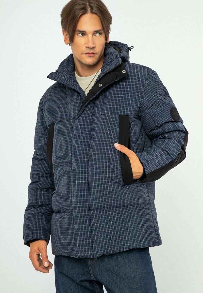 Námořnický puf z bundy s kostkovaným vzorem, kapucí, černými akcenty, předními kapsami a texturovaným povrchem. Obsahuje zip a knoflíkové zavírání.