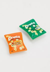 Two snack bags in vibrant colors: one orange labeled "Sour Cream and Cheddar," one green labeled "Sour Cream and Onion." Both have shiny textures.
