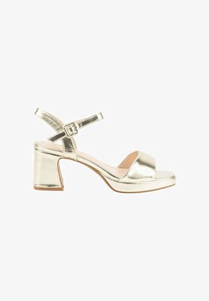Sandalias de tacón metálicas doradas con punta abierta, correa en el tobillo y tacón cuadrado grueso. Textura suave con acabado reflectante y detalle de hebilla.