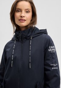 Marineblaue Sweatjacke mit Reißverschluss und Kapuze. Mit Logodetails auf der Brust und am Ärmel, Kordelzug am Hals und einer glatten Stoffstruktur.