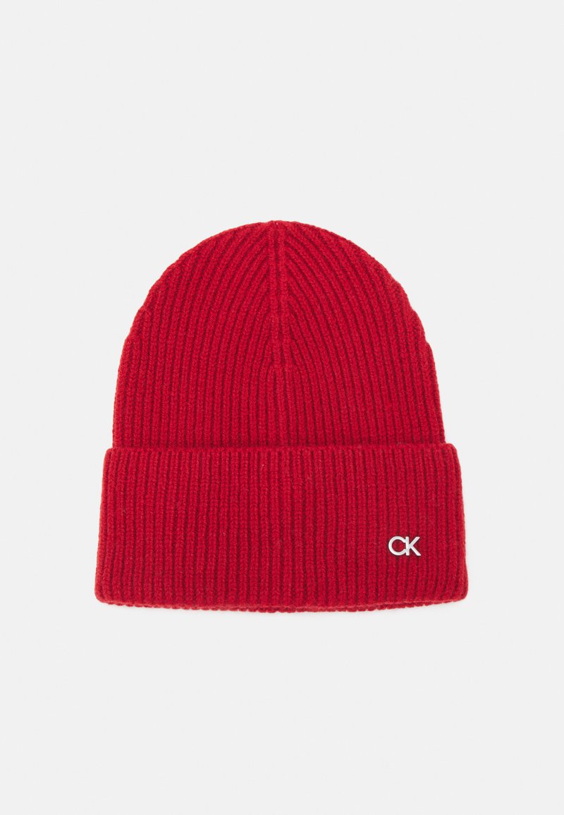 Red knitted beanie with ribbed texture and folded cuff. Features small white "CK" logo on the cuff. Made from soft, stretchy material.