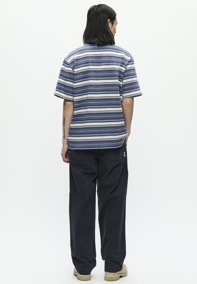 Chemise à manches courtes rayée aux couleurs bleu et crème, avec une coupe décontractée et un col au dos. Associée à un pantalon sombre et ample.
