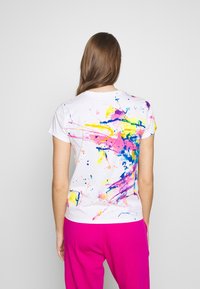 Bílý bavlněný tričko s živým designem rozstřiku barev v růžové, žluté, modré a fialové. Krátké rukávy a kulatý výstřih.