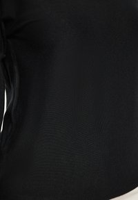 Top negru ajustat dintr-un material ribat, cu o textură netedă și mâneci lungi. Designul este simplu, fără modele sau ornamente vizibile.