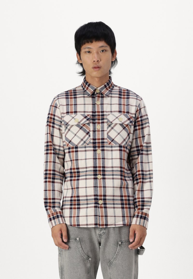 Langearmige geruite shirt in crème, blauw en roesttinten, voorzien van twee borstzakken, knoopsluiting en een puntige kraag van zachte stof.