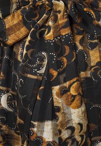 Gefalteter Stoff in Schwarz und Gold mit floralem und geometrischem Muster. Ausgestattet mit einem gebundenen Gürtel und glatter Textur.