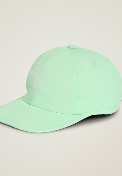 Gorra de béisbol verde claro con paneles cosidos y un logo circular en el lado frontal izquierdo, colocada sobre una superficie de color claro.