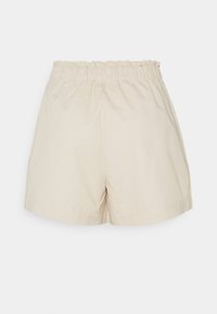 Shorts beige à taille élastique avec une coupe ample et une ceinture légèrement froncée, présentés sur un fond uni.
