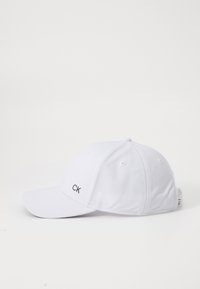 Fehér baseball sapka strukturált dizájnnal, hálós anyagból készült. Az elején hímezett "CK" logó található. Simább karima.