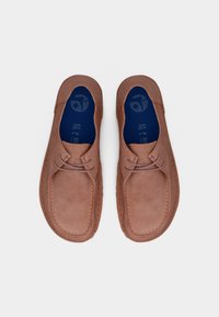 Ζευγάρι καφέ σουέντ καθημερινά παπούτσια με μπλε εσωτερικά πέλματα, σχέδιο με κορδόνια και ανθεκτικό ράψιμο, εμφανιζόμενα από πάνω προς τα κάτω.