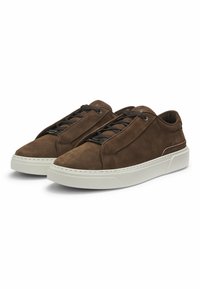 Ein Paar braune Wildleder-Low-Top-Sneaker mit schwarzen Schnürsenkeln und dicken weißen Gummisohlen auf einem weißen Hintergrund.