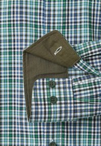 Geruite overhemd met groene, marineblauwe en witte kleuren; heeft groene knopen, een contrasterende bruine visgraatmanchet en een decoratieve witte stiksel.