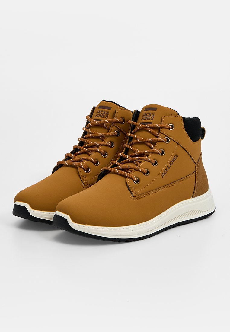 Tanfarbene High-Top-Schuhe mit einem synthetischen Obermaterial, hellbraunen Schnürsenkeln, weißer Mittelsohle und einem schwarzen Akzent am Kragen. Logo an der Seite. Gummisohle.