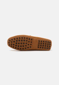 Suede hjemmesko-sål i lys brun med sorte gummi-dot greb. Flad og rund form designet til komfort og godt fodfæste. Renset, minimalisk design.