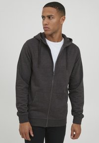 Dark grey zip-up hoodie made of soft fabric, featuring a drawstring hood, front pockets, and ribbed cuffs for a snug fit.