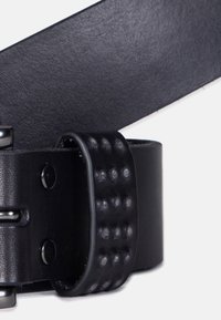 Sort læderbælte med en glat overflade og prægede prikmønstre i spændeområdet. Har sølvfarget metalbeslag og et klassisk design.