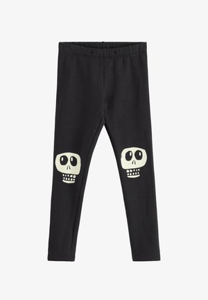 Juodos leggingai su minkšta tekstūra turi du baltus kaukolės dizainus ant kelių. Juosmens juosta yra elastinga patogumui ir lengvam užsidėjimui.