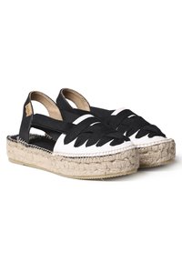 Sandali espadrilles in bianco e nero con tomaia in tessuto intrecciato, tacco aperto e suola avvolta in juta. Presentano cinturini incrociati e suola piatta in gomma.