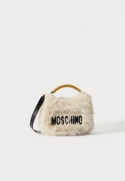 Sac à main en fausse fourrure beige avec le logo noir "MOSCHINO". Doté d'une poignée arrondie dorée et d'une bandoulière noire amovible.