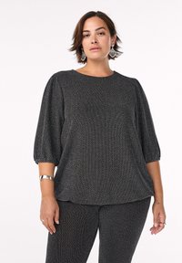 Juoda ir sidabrinė bluzonė su hemborono raštu, trumpomis pūstomis rankovėmis ir apvaliu kaklu, pagaminta iš tekstūrinio audinio.