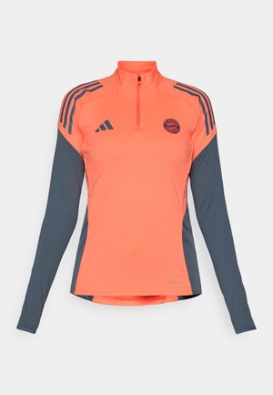 Long-sleeve athletic top featuring a half-zip design, vibrant coral body, gray sleeves, three black stripes, and a circular logo on the chest.