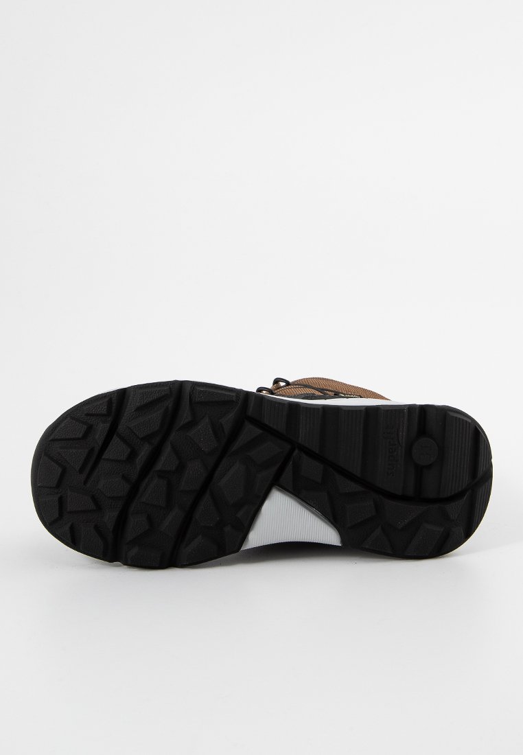 Braune Wanderschuhe mit einer strukturierten, schwarzen Gummisohle; verfügen über ein strapazierfähiges Obermaterial mit Schnürung und ausgeprägten Traktionsmustern auf der Sohle.