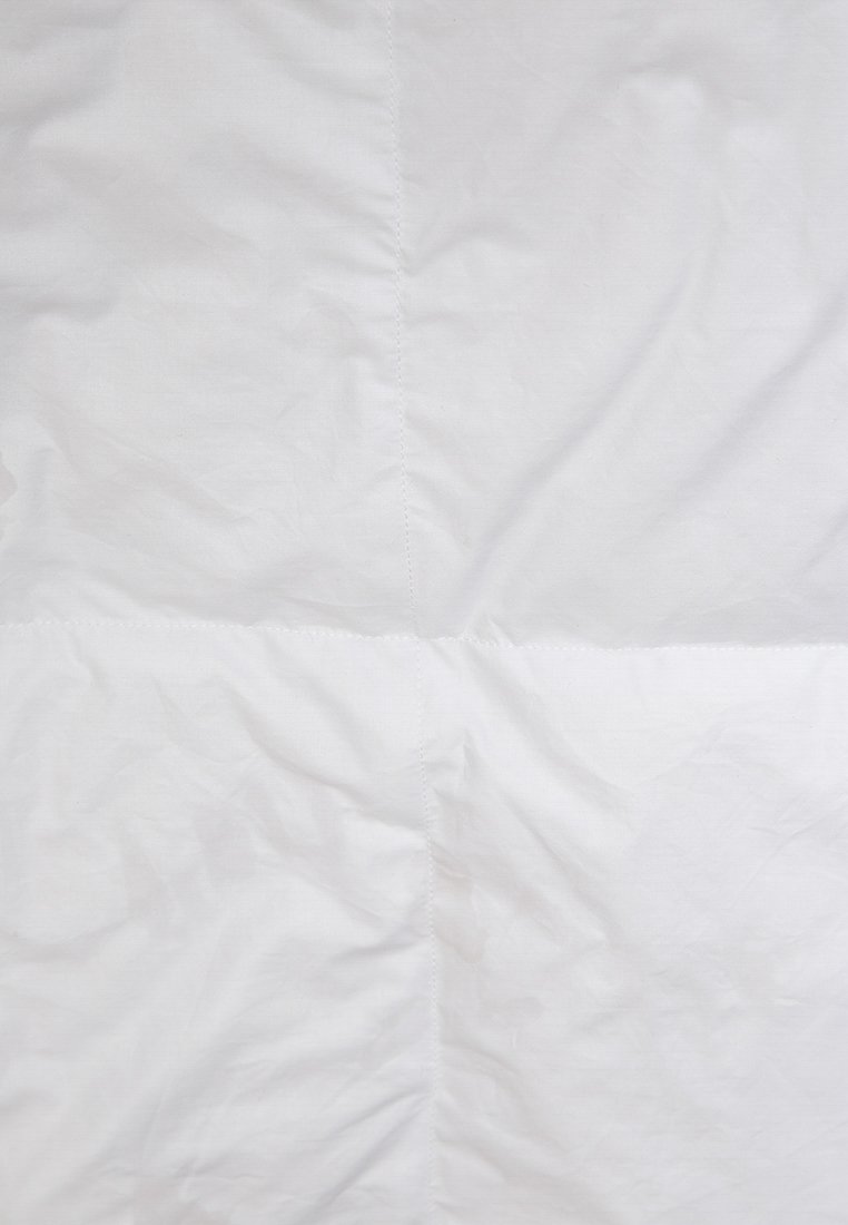 Weißer Stoff mit glatter Textur, der dezente Falten und eine genähte Naht aufweist, die zwei Abschnitte teilt. Keine Muster oder Akzente sichtbar.