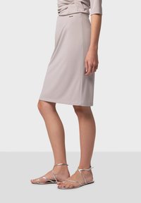 Robe gris clair à mi-mollet avec un corsage torsadé, associée à des sandales argentées à lanières. La robe présente un design sans couture et une texture douce.