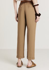 Pantaloni marroni, leggeri, a vita alta con elastico in vita, gamba dritta, risvolti e due tasche posteriori.