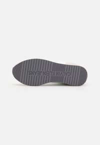 Suela de zapatilla Calvin Klein Jeans. Goma gris claro con surcos horizontales y verticales prominentes. Incluye el nombre de la marca en relieve en el centro.
