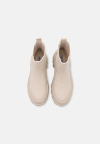 Bottines beiges en cuir lisse, semelle en caoutchouc et languettes à l'arrière pour un enfilage facile. Bout arrondi et design épuré.