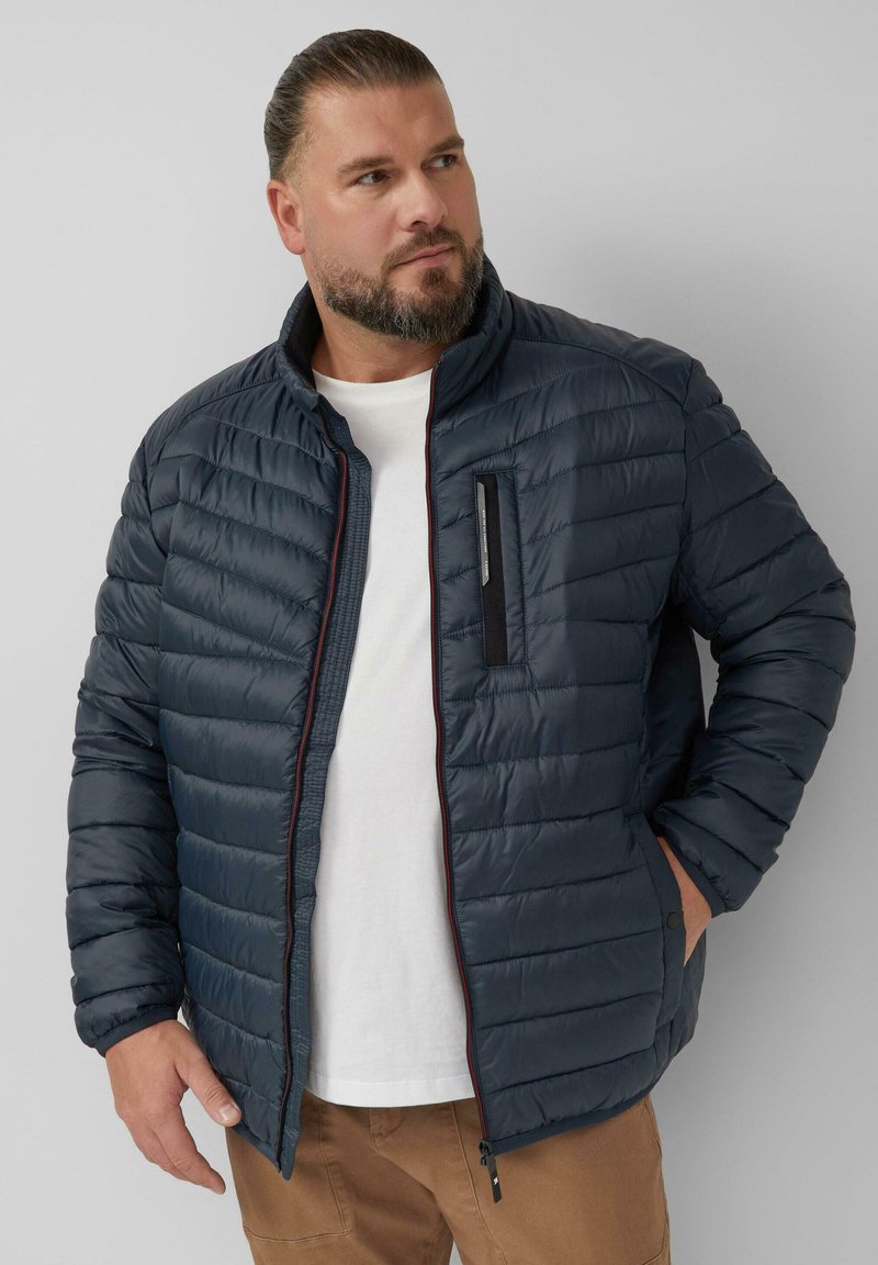 Dunkelblaue gepolsterte Jacke mit gestepptem Muster, hohem Kragen und kontrastierendem roten Reißverschluss. Verfügt über eine Brusttasche und Seitentaschen.