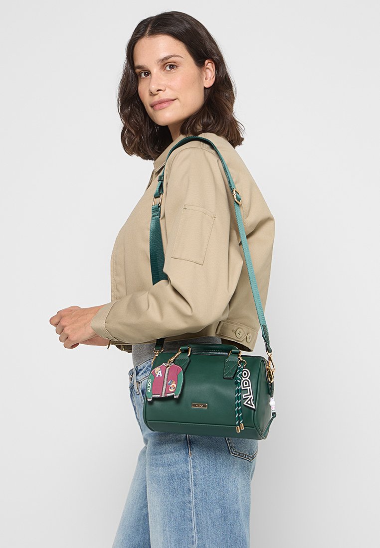 Borsa a tracolla verde in pelle con hardware dorato, forma strutturata, tracolla rimovibile e etichette decorative in colori contrastanti.