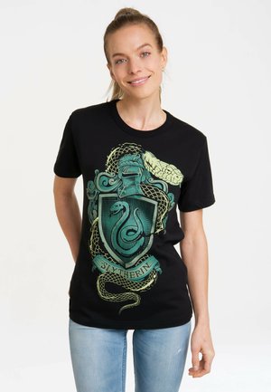 Black cotton t-shirt featuring a green Slytherin emblem with a serpent and decorative elements. Short sleeves and classic crew neck design.