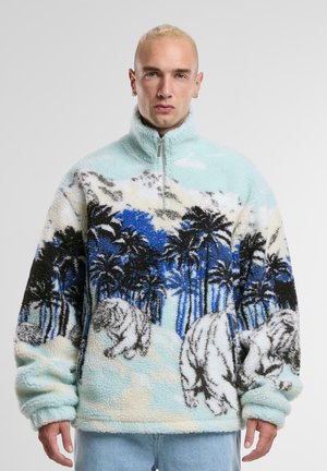 Fleece pullover with a light blue base, featuring black and white polar bears and palm trees. Zip neck design with soft, textured fabric.