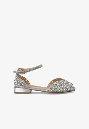 Chaussure argentée à brides de cheville avec un petit talon, embellie de strass et de motifs découpés sur les côtés pour la ventilation.