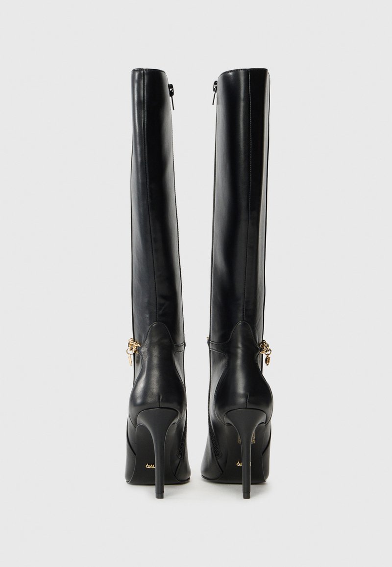 Zwarte leren kniehoge laarzen met een strak ontwerp, spitse neuzen, hoge stiletto-hakken en gouden hardware accenten bij de enkel.