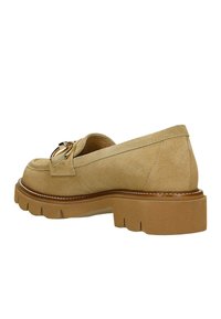 Beige Wildleder-Mokassins mit einer robusten Gummisohle und dekorativem goldenen Zubehör, mit einer abgerundeten Zehenform und gestickten Details.