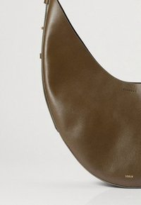 Ruskea nahkainen olkalaukku, jossa on kaareva muoto, sileä pinta ja hienovaraiset kullanväriset metalliosat, joissa on brändinimi "Soeur".