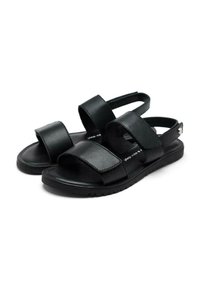 Sandalias negras con correas sintéticas, cierres de Velcro ajustables, suela acolchada y una suela exterior de goma texturizada para agarre.